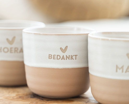 Theemok met bedankt erop met daarboven een hartje. De bovenkant van de mok is wit en de onderkant van de mok is steenoranje.